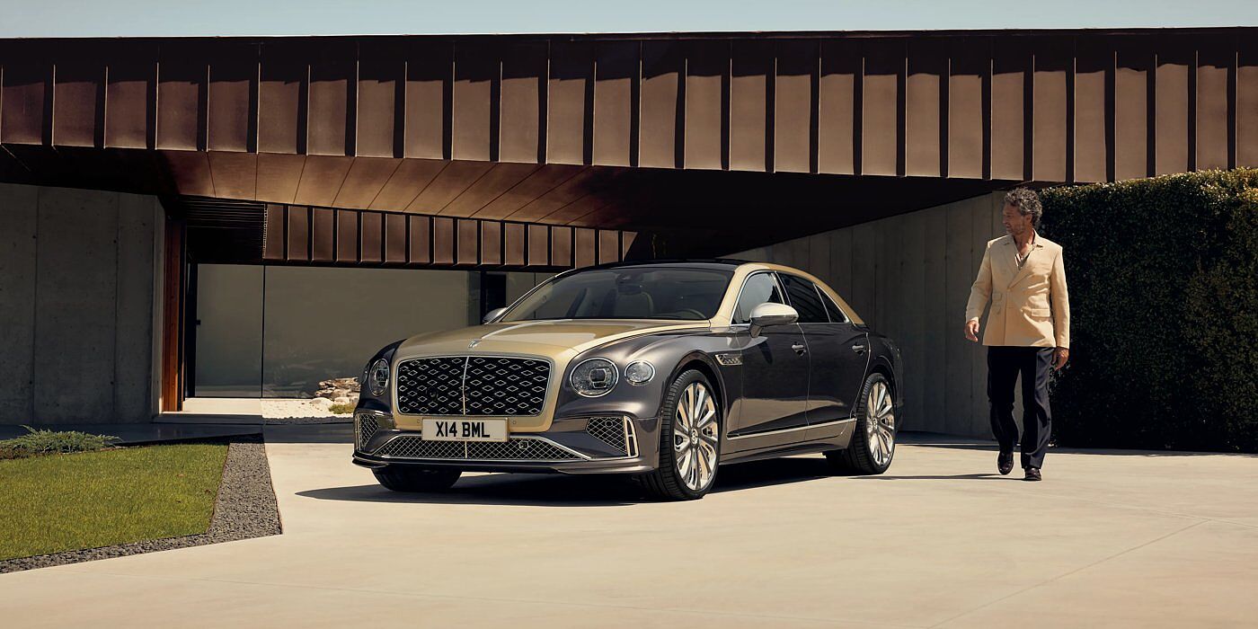 Bentley Macau Bentley New Flying Spur Mulliner V8 hybrid sedan front three quarters in Rose Gold over Magnetic paint, parked near modern home