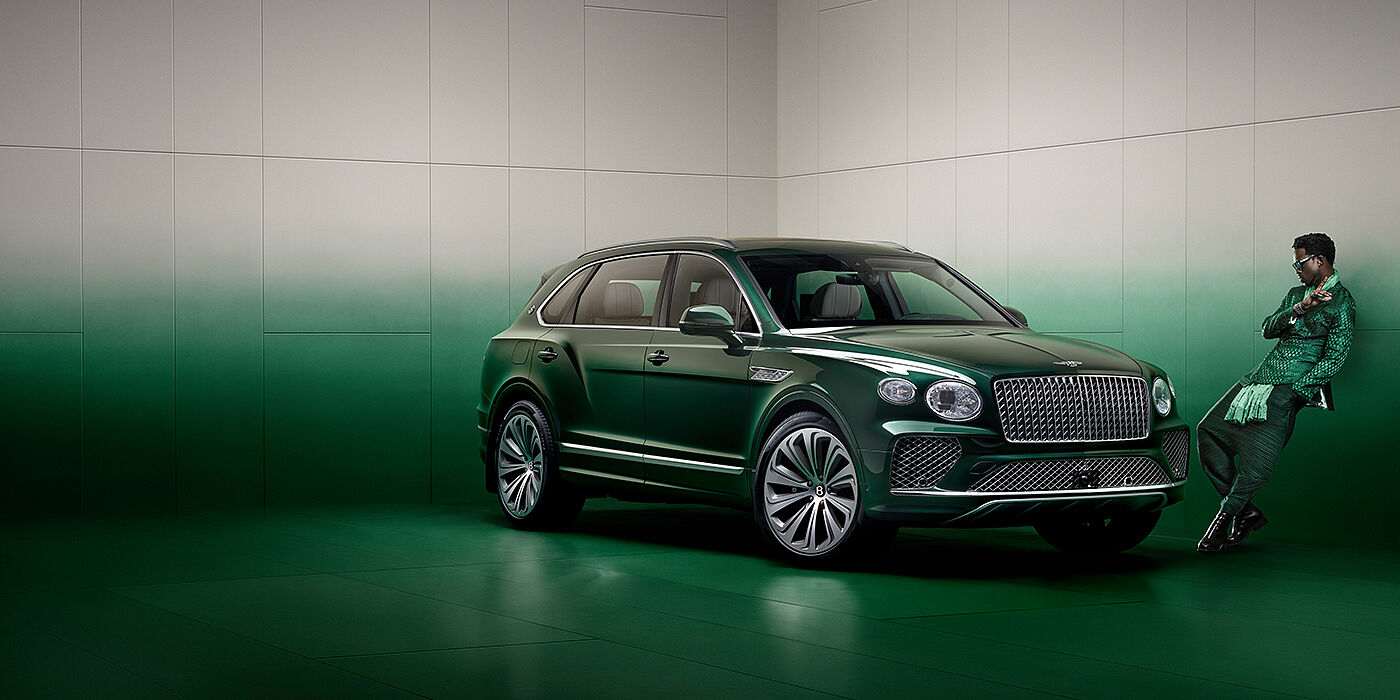 Bentley Macau Wisdom K leans against wall next to Bentley Bentayga Extended Wheelbase Atelier Edition SUV in Light Emerald green paint