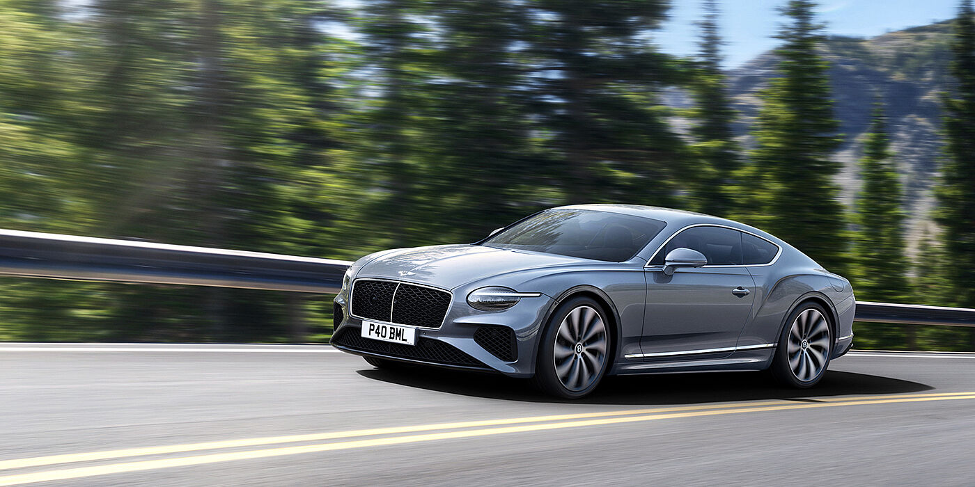 Bentley Macau New Bentley Continental GT coupe in Silverlake paint and 22 inch ten-spoke wheels, driving dynamically on a tree-lined road in the sunshine