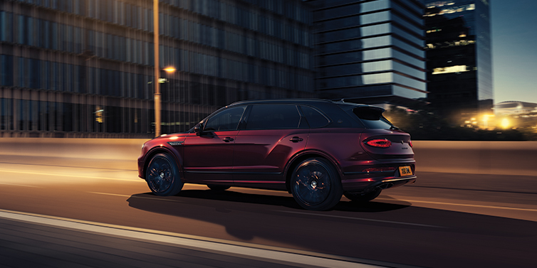 Bentley Macau Bentley Bentayga Extended Wheelbase Mulliner SUV in Cricket Ball red paint driving dynamically in city at night
